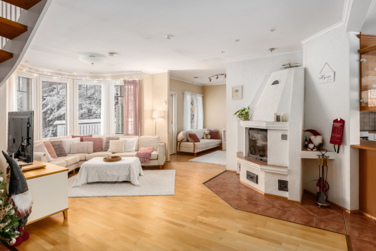 Sala con sofás claros, chimenea blanca y grandes ventanas con vistas a árboles nevados