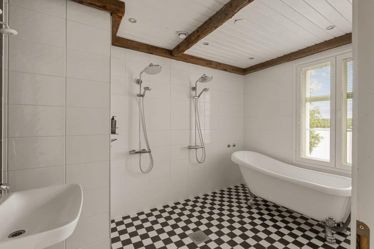 Baño con bañera de patas, dos duchas de lluvia y suelo ajedrezado en blanco y negro