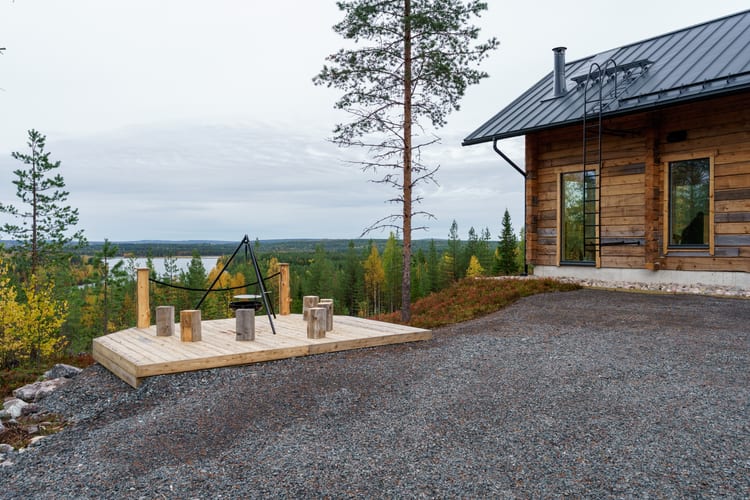 Nuotiopaikka riippupatoineen syksyisellä terassilla, järvi horisontissa