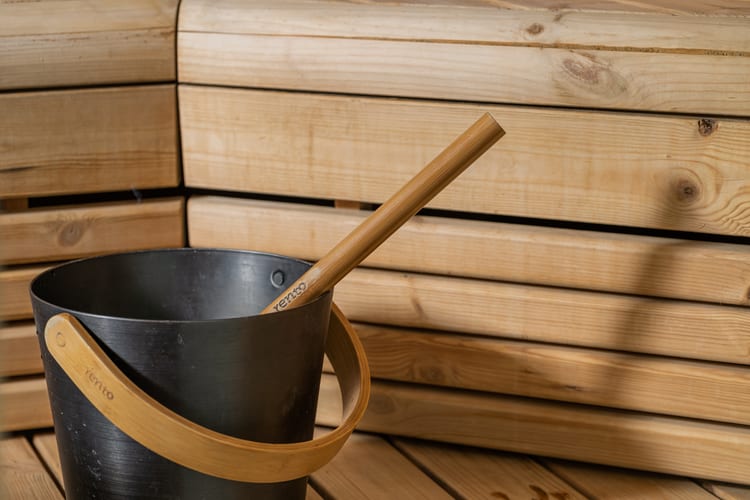 Musta kiulu ja puinen kauha saunan lauteilla lämpimässä puupinnassa